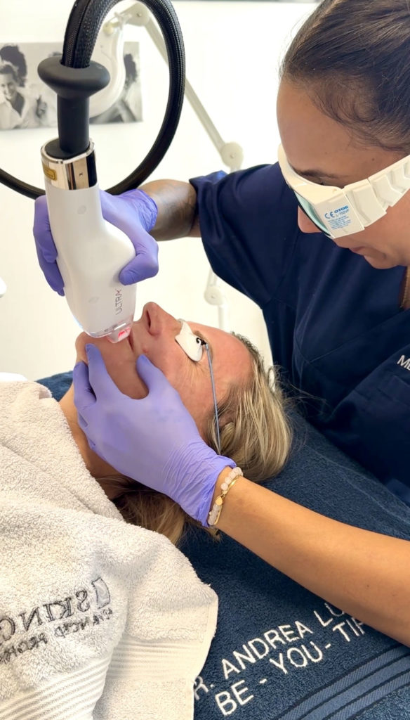 Eine liegende Dame erhält eine Laserbehandlung im Gesicht
