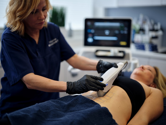 Dame wendet die Hautstraffung mit dem dafür vorhergesehenen Ultraschallgerät an.